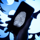 In this photo illustration, a thumbprint is displayed on a mobile phone as the logo for the Twitter social media network is projected onto a screen on August 09, 2017 in London, England.